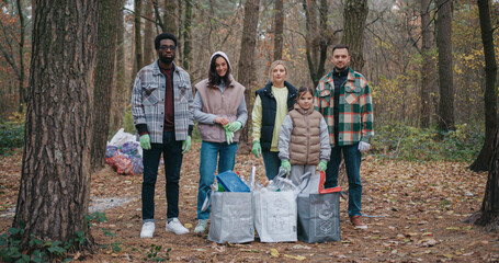 Portrait of group of volunteers standing together and looking at camera. People wearing gloves for...