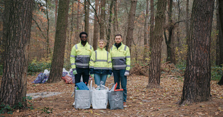 Caring volunteers standing together while looking directly at camera. Serious facial expression....