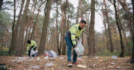 Camera showing modern problems of plastic pollution. People actively trying collecting garbage from...