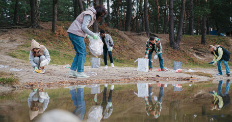People showing teamwork while helping nature. Placing garbage into specific bags for recycling....