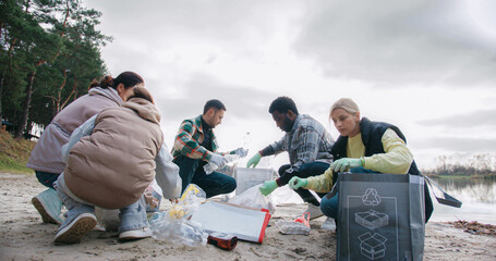 Group of friends spending free time by volunteering. Cleaning up nature from plastic waste. Picking...