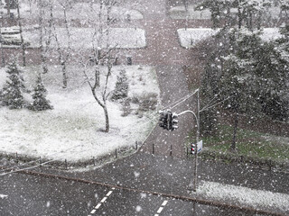 View from the window over heavy fluffy snow falling over the pedestrian crossing with red traffic...