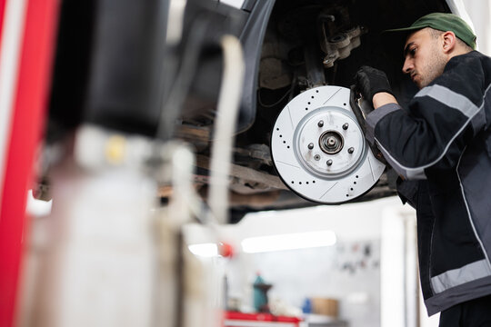 Mechanic inspecting car brake disc in auto repair shop