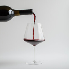 pouring red wine into a glass on a white background 