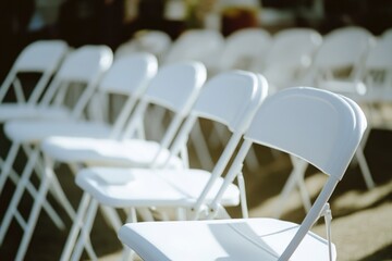 A row of white folding chairs placed on the edge of a sidewalk, possibly for an outdoor event or ceremony