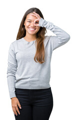 Fototapeta premium Young beautiful brunette woman wearing sweater over isolated background doing ok gesture with hand smiling, eye looking through fingers with happy face.