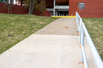 The exterior wall of a large brick building and a new concrete sidewalk. There's a...