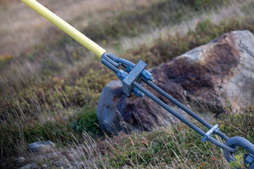 A guy wire secured to the ground from a distribution utility pole. The galvanized wire is wrapped...