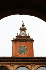 A clocktower in Bologna, Italy seen from the arcade of a nearby building