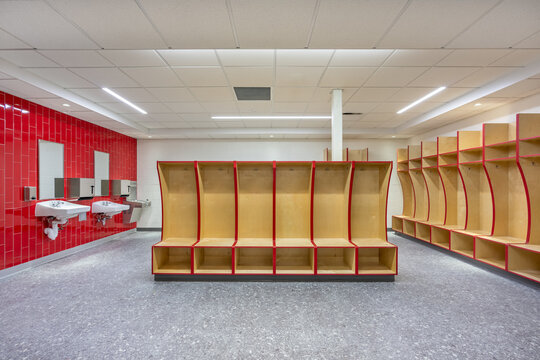 Empty team locker, changing room with traditional open wooden lockers with a red trim.