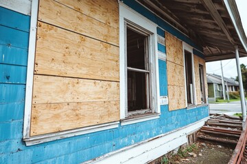 A blue and white house with boarded windows, perfect for use in crime or mystery scenes