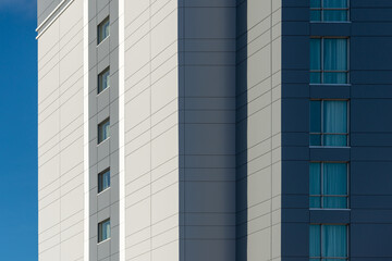 The exterior wall of a contemporary commercial style building with aluminum metal composite panels and glass windows. The futuristic building has engineered diagonal cladding steel frame panels.