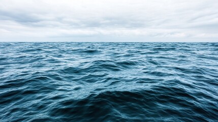 Waves gently roll across an expansive ocean as clouds hover above during early morning hours, creating a serene and tranquil atmosphere filled with natural beauty