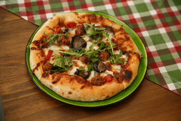 Delicious pizza served on wooden table with green plaid tablecloth. Italian cuisine concept