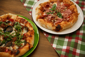 Delicious pizza served on wooden table with green plaid tablecloth. Italian cuisine concept