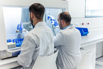 Scientists working with micropipettes in laboratory fume hood
