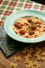 Macaroni pasta with meat pieces in tomato sauce and vegetables in bowl. Top view. Traditional Italian cuisine