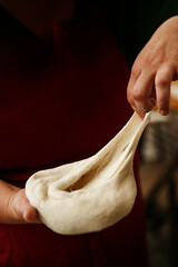 woman chef is kneading dough by hand. There is a rolling pin and flour in a bowl and on countertop...