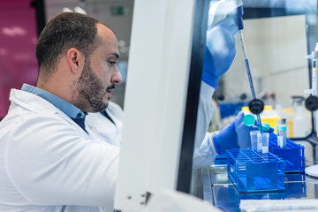 Scientist pipetting liquid into test tubes inside a sterile cabinet in laboratory