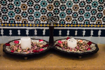 Fes, Morocco. Interior of a women's hammam. Tray of dried roses and candles by bath area.