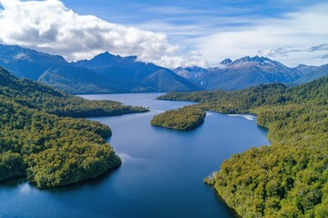 Glistening waters reflect the majesty of mountains in a serene New Zealand landscape under a clear sky