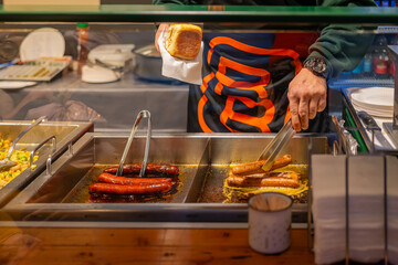 Grilled sausages being prepared at a food stall by male cook. Concept of fast food and street food...