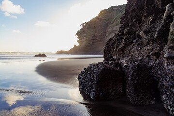 Dramatic coastal scene at sunrise. Dark volcanic rocks meet the tranquil ocean. Peaceful morning...
