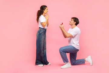 Romantic man kneeling making proposal to his beloved girlfriend, guy presenting engagement ring to...