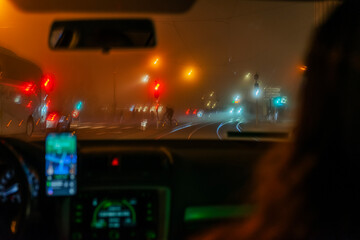 Blurred View of a foggy urban street through car windshield at night. Concept of night driving and...