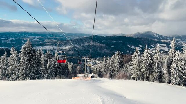 Ski lift ride through snow-covered mountains in winter landscape at a ski resort