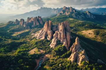 Naklejka premium Majestic rock formations rise dramatically in the lush green landscape against the backdrop of a cloudy sky at golden hour