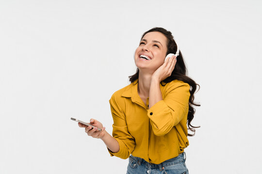 Enjoyed smiling young woman girl listening to music song audio in headphones earphones, dancing singing choosing sound track podcast e-book isolated in white background.