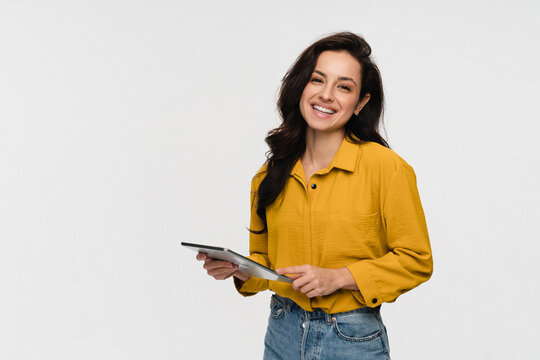 Smiling woman girl student holding using tabled pad for for remote work, e-learning at university college, e-banking, online shopping, webinars social media isolated over white background