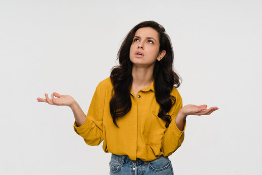 Portrait of hispanic latin questioned indecisive woman girl student with dark curly hair shrugging and throwing hands aside with clueless looking up isolated over white color background