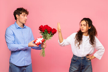 Displeased European lady rejecting her boyfriend with roses and gift on Valentine's Day, man giving...