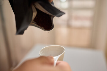 Pouring freshly ground coffee beans into a measuring cup for a perfect morning brew