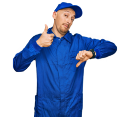 Bald man with beard wearing builder jumpsuit uniform doing thumbs up and down, disagreement and agreement expression. crazy conflict