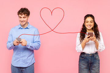 Positive European lady and guy chatting online via phones connected with drawn heart shape string, typing love messages to each other