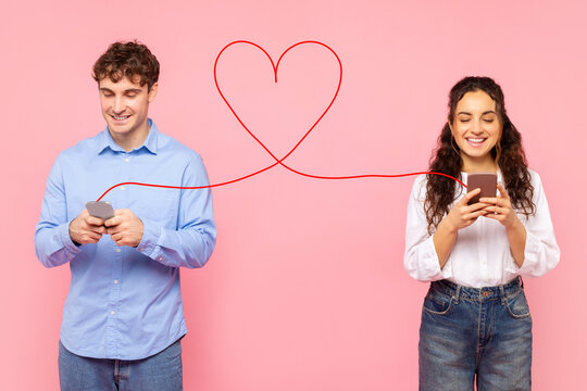 Positive European lady and guy chatting online via phones connected with drawn heart shape string, typing love messages to each other