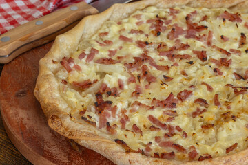 tarte flambée (Flammekueche) alsacienne, en gros plan, sur une planche à découper