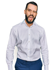 Young man with beard wearing business shirt winking looking at the camera with sexy expression, cheerful and happy face.