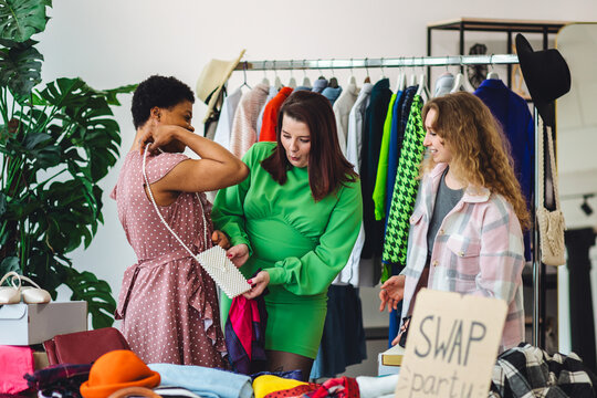 Girls having fun at home swap party. Garage sale, second hand, trying used clothes, exchanging jeans, dresses, accessories . Sustainable fashion, conscious consumption, circular economy concept