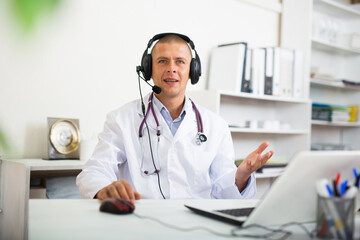 Hotline service. Doctor consulting patient online via laptop indoors. Telemedicine concept