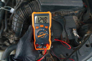 Test car battery with multimeter in cold season. Checking car battery voltage with multimeter while...