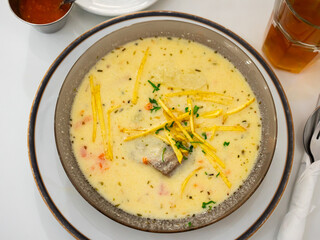 Hearty Latin American peanut soup, sopa de mani, with short tube noodles and meat. In Bolivian tradition, served with crispy fried potatoes and greens