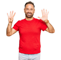 Handsome middle age man wearing casual red tshirt showing and pointing up with fingers number nine while smiling confident and happy.