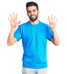 Fototapeta premium Young handsome man with beard wearing casual t-shirt showing and pointing up with fingers number nine while smiling confident and happy.