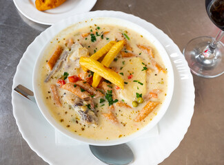 Traditional bolivian peanut and potato soup de mani made from beef broth, potatoes, carrots and spices is served on plate. Food is decorated with slices of French fries, served with glass of beer