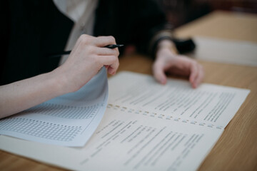 Close-up of hands with a notebook on the exam table. A student takes a test at his desk, writes a task in a notebook in the classroom © Anna