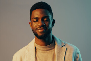 A joyful young African man in a light colored blazer with a warm smile, showcasing confidence and positivity against a soft gradient backdrop